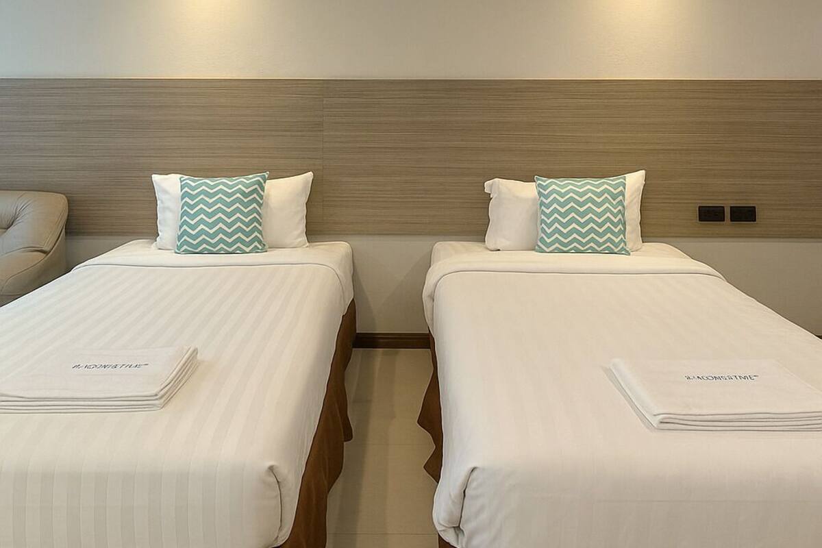 A hotel room with two beds, each with a white bedspread and a matching pillow.