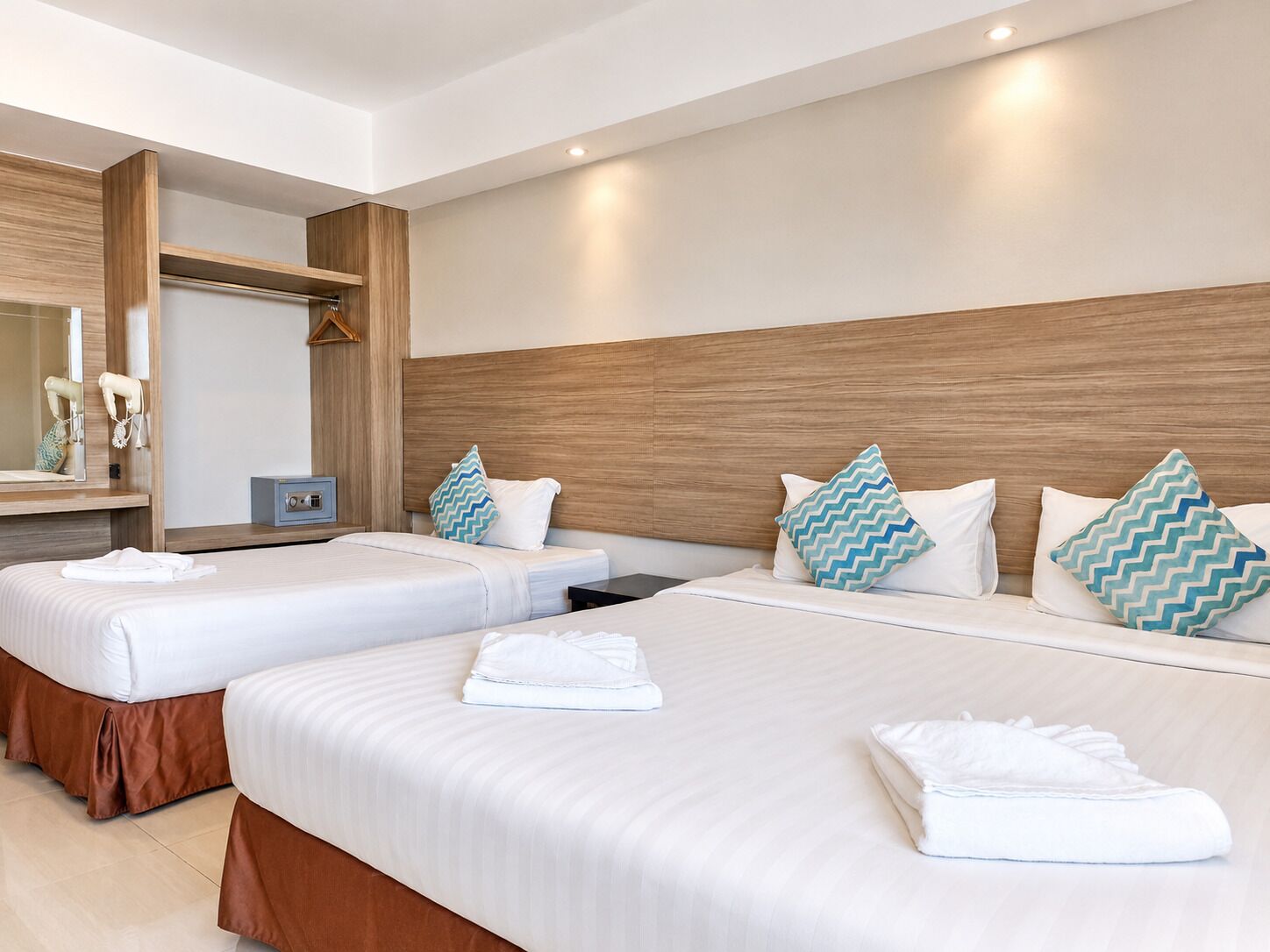 A hotel room with two beds, a mirror, a vanity, and a small table.
