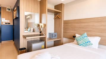 Habitación de hotel con cama, mesita de noche, espejo, armario y un pequeño escritorio con silla.