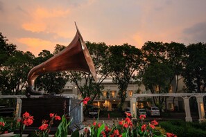 Une grande sculpture métallique, placée en plein air, avec un bâtiment en arrière-plan.