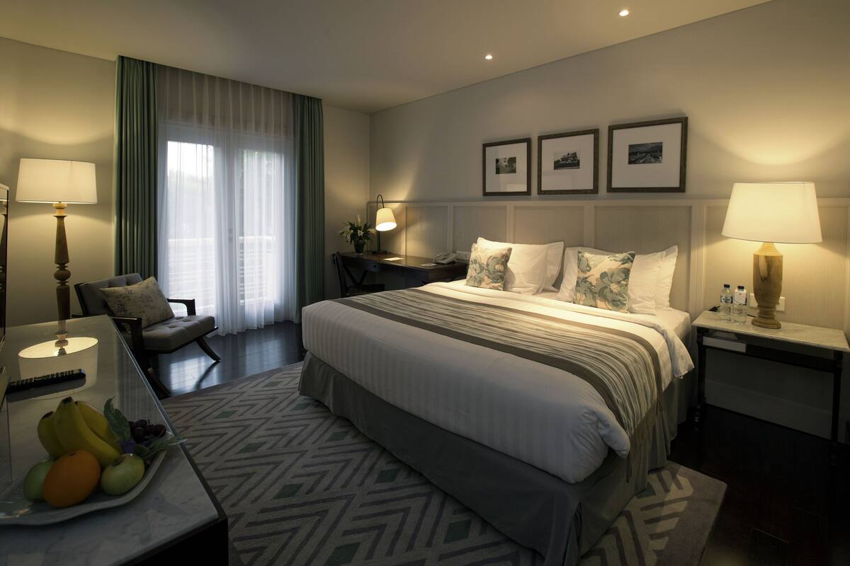 Une chambre d’hôtel moderne avec un grand lit, un bureau, une chaise et une table à manger agrémentée de fruits.