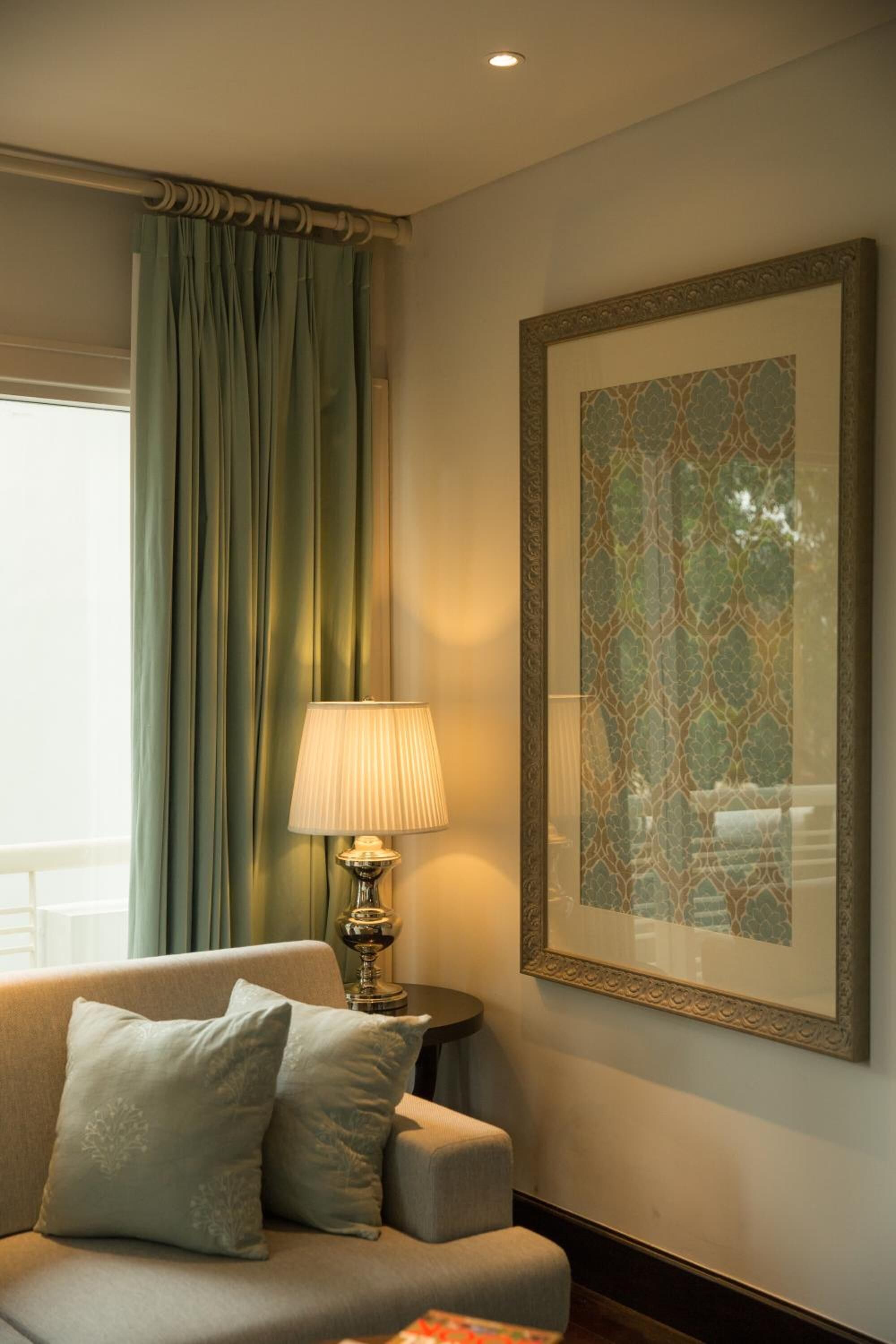 A room with a sofa, a lamp, and a framed picture on the wall.