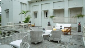 Une terrasse sur le toit, aménagée avec des meubles en osier, des lanternes et des plantes en pot.