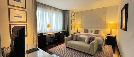 A hotel room with a bed, a desk, a television, and a patterned rug.