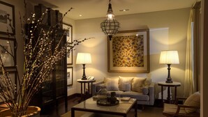 Un salon chaleureux avec un canapé, une table basse et des lampes. On y trouve un vase avec des branches et un tableau encadré accroché au mur.
