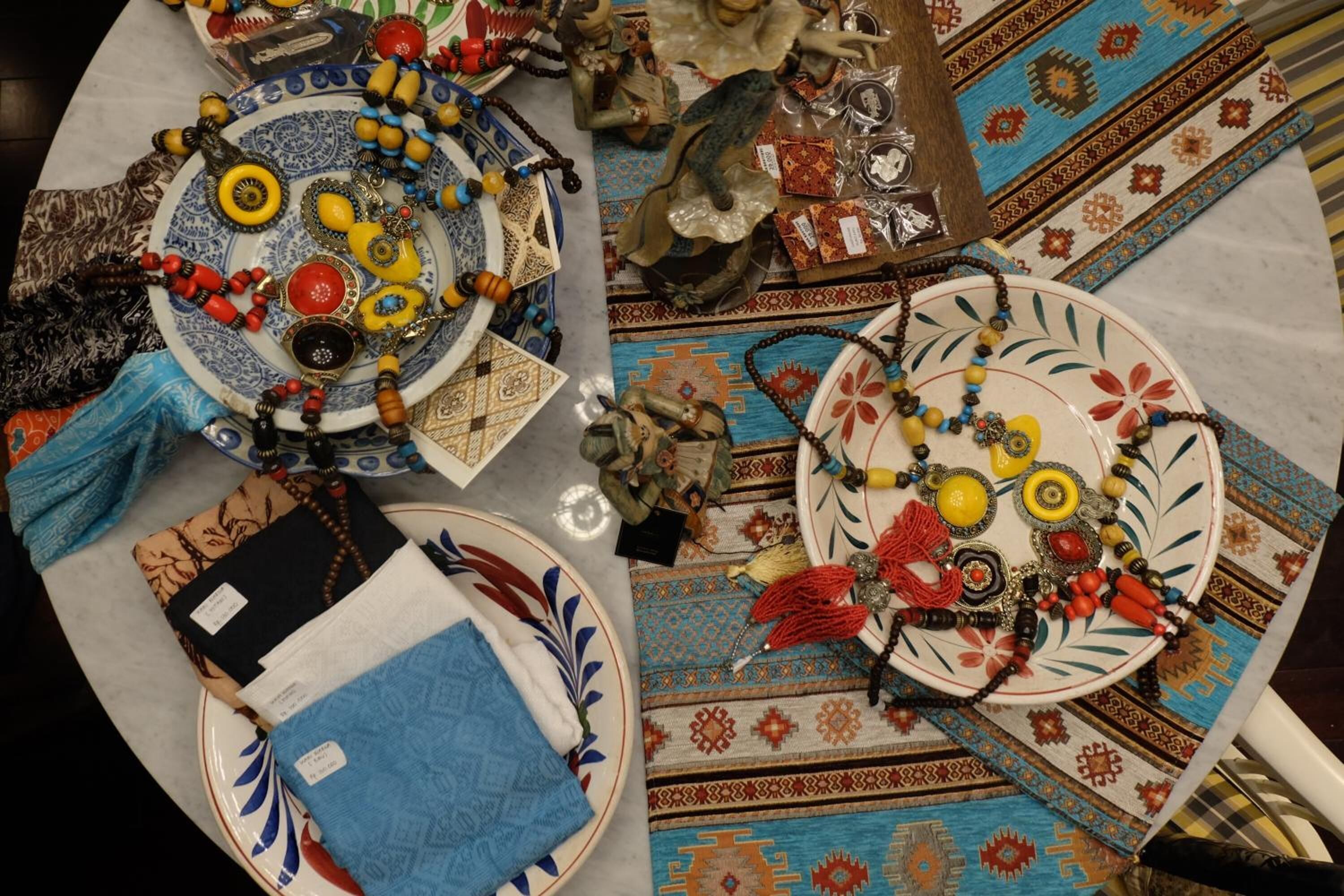 A table with various decorative items including plates, beads, and textiles.