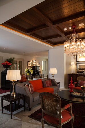 Un salon spacieux avec un haut plafond, un lustre et une cheminée.