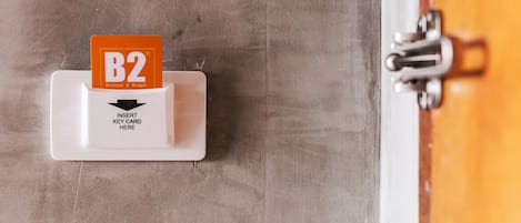 Un lector de tarjetas con una tarjeta B2 insertada, un cartel que indica insertar la llave y un pestillo metálico en una puerta.