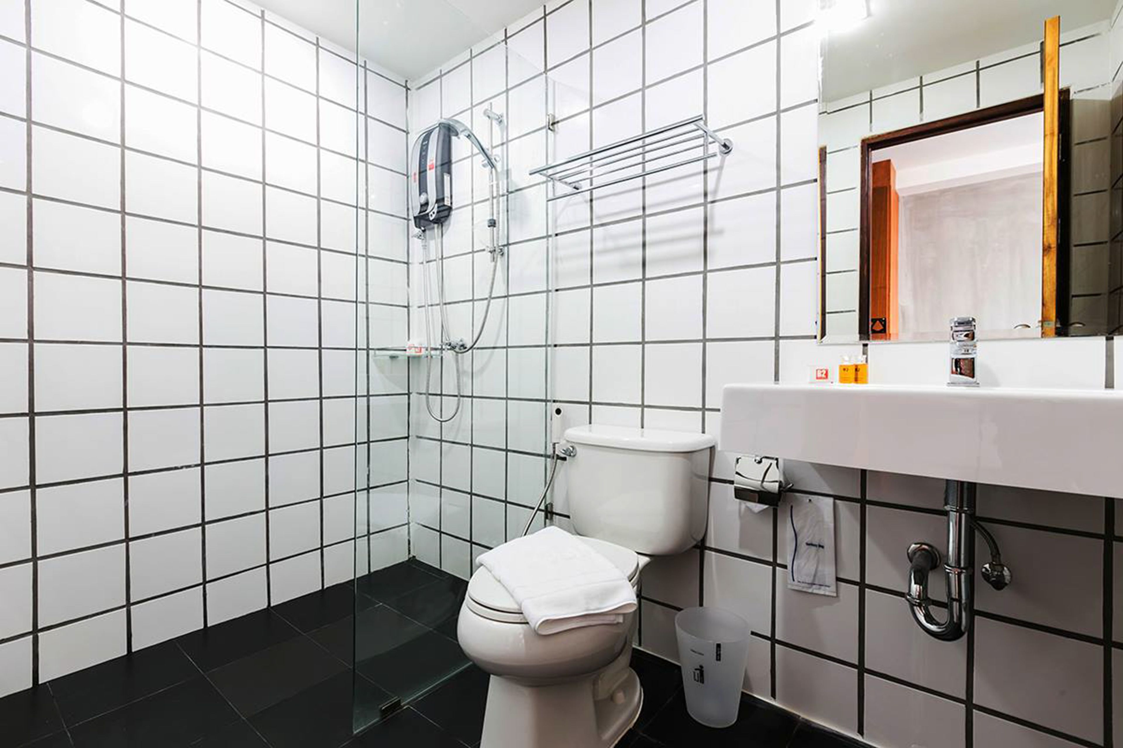 A modern bathroom with a white toilet, a glass shower enclosure, and a white sink with a mirror above it.