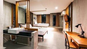 A modern hotel room with a large bed, a separate sitting area with a desk and chair, a large mirror, and a bathroom with a sink and vanity. - B2 Khon Kaen Boutique & Budget Hotel (Khon Kaen)