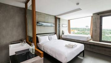 A modern hotel room with a large bed, a bedside table with a mirror, a window with a view, and a bathroom with a sink and mirror.