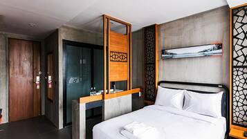 Quarto de hotel moderno com uma cama grande, uma escrivaninha de madeira, área de chuveiro e vista para uma paisagem nevada.
