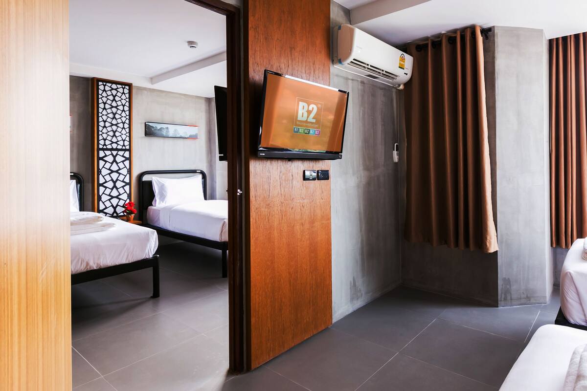 Ein Hotelzimmer mit zwei Betten, einem Fernseher, einer Klimaanlage und Blick zum Himmel.