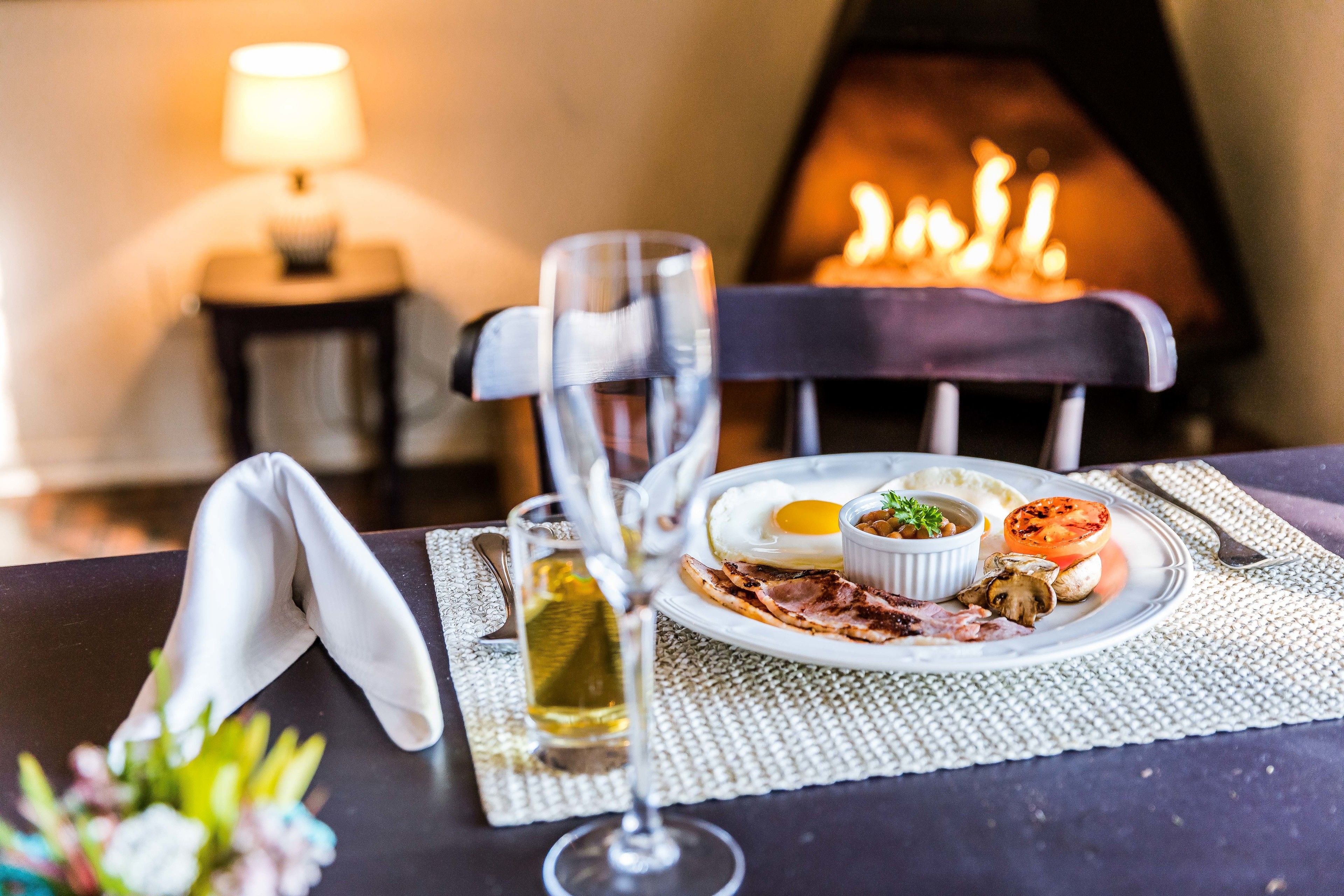 A dining table with a plate of food, a glass of wine, and a napkin.