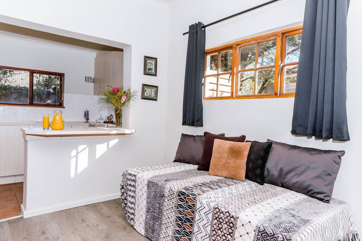 Ein modernes Schlafzimmer mit einem großen Bett, einer kleinen Küchenzeile und einem Fenster mit Vorhängen.