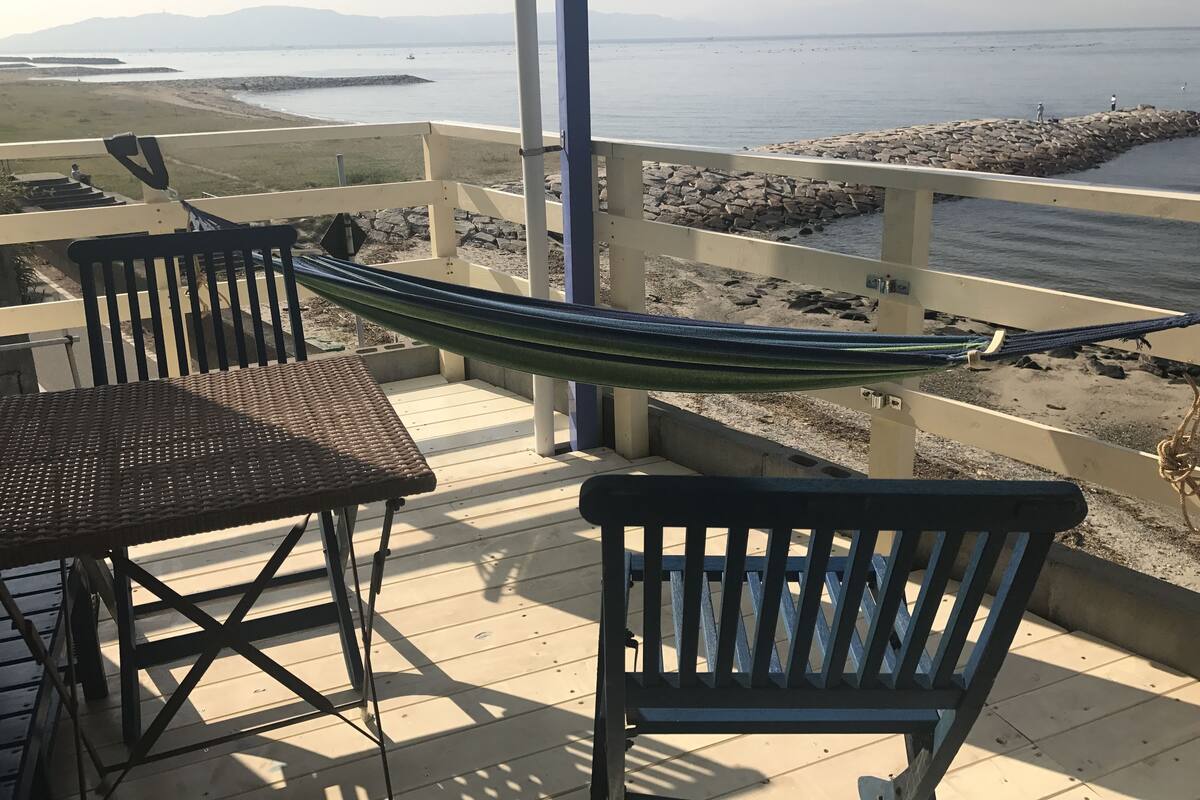 Ein Balkon mit Hängematte, Stühlen und Meerblick.