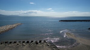 A coastal scene with a rocky breakwater, calm sea, and clear sky. - Guest House Lohas Home (Akashi)