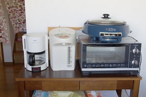 Un taulell de cuina amb una cafetera, una cocedora d'arròs i un forn elèctric per torrar pa.