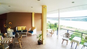 A spacious balcony with a view of a river, furnished with chairs and a sofa.
