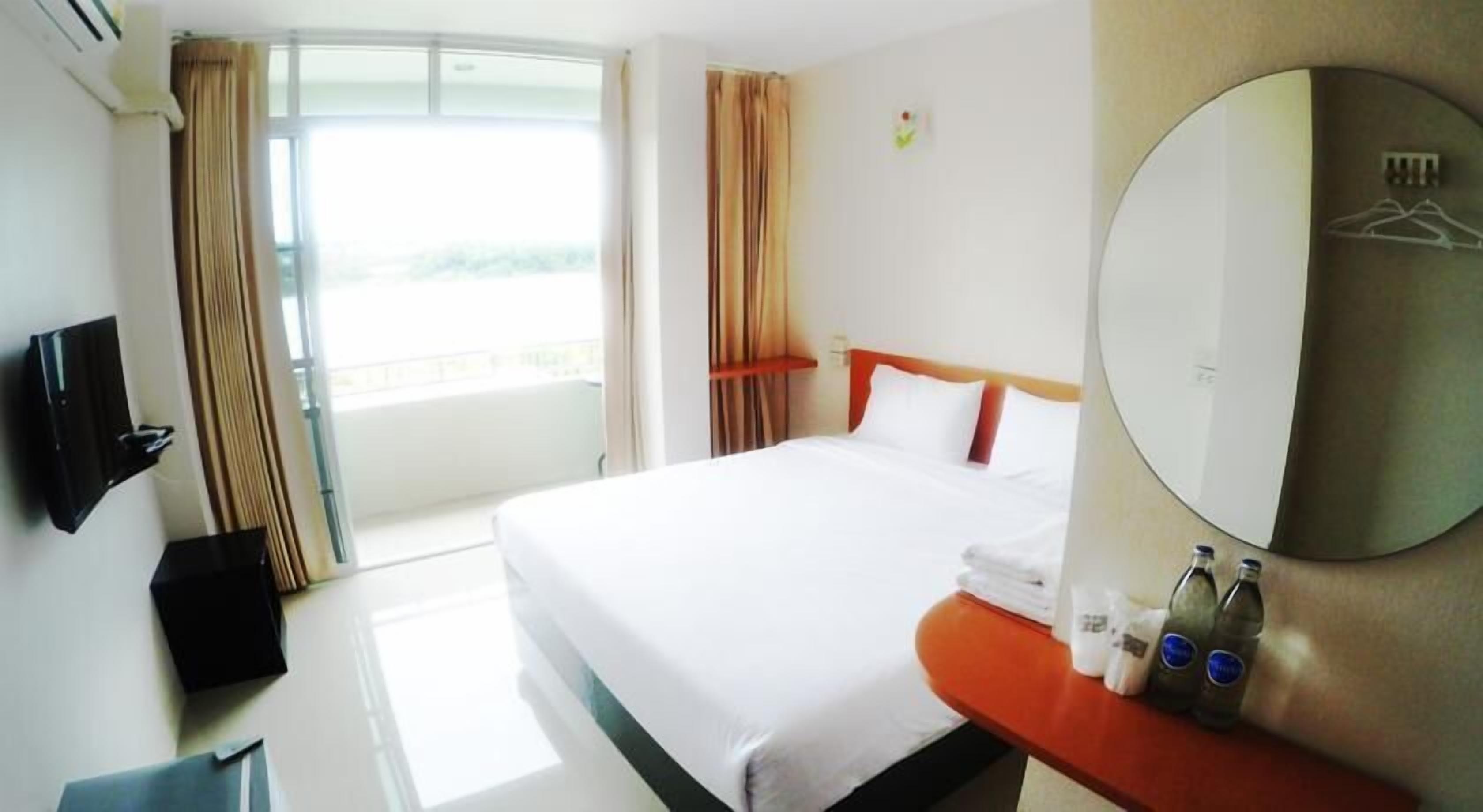 A hotel room with a bed, a TV, a bathroom, and a balcony.