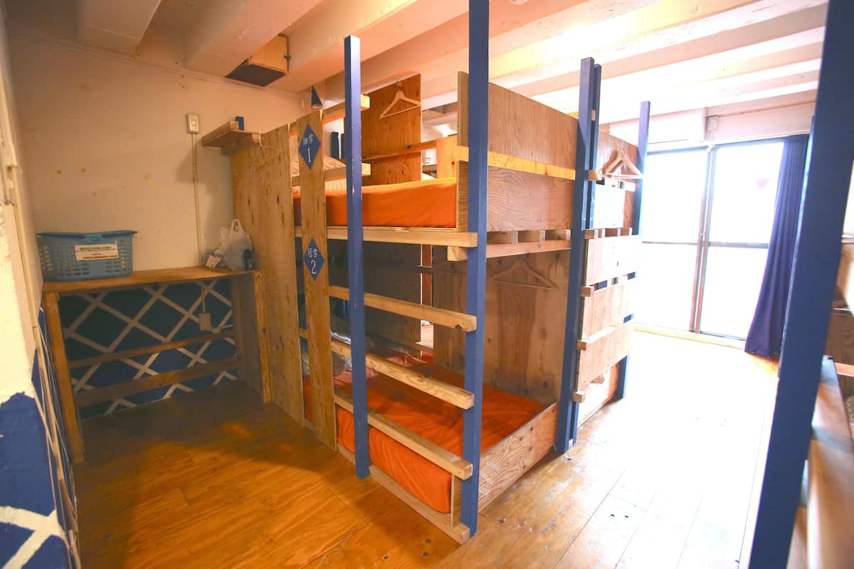 Une chambre avec un lit superposé, des poutres en bois et un mur bleu.
