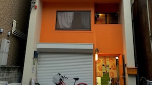 A two-story building with a red bicycle parked in front. - Yadoya Guest House Orange - Hostel (Tokyo)