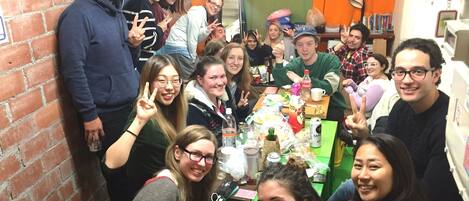 A group of people gathered around a table in a room with brick walls and a green tablecloth.