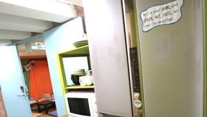 A kitchen with a refrigerator, microwave, and a small dining table. - Yadoya Guest House Orange - Hostel (Tokyo)