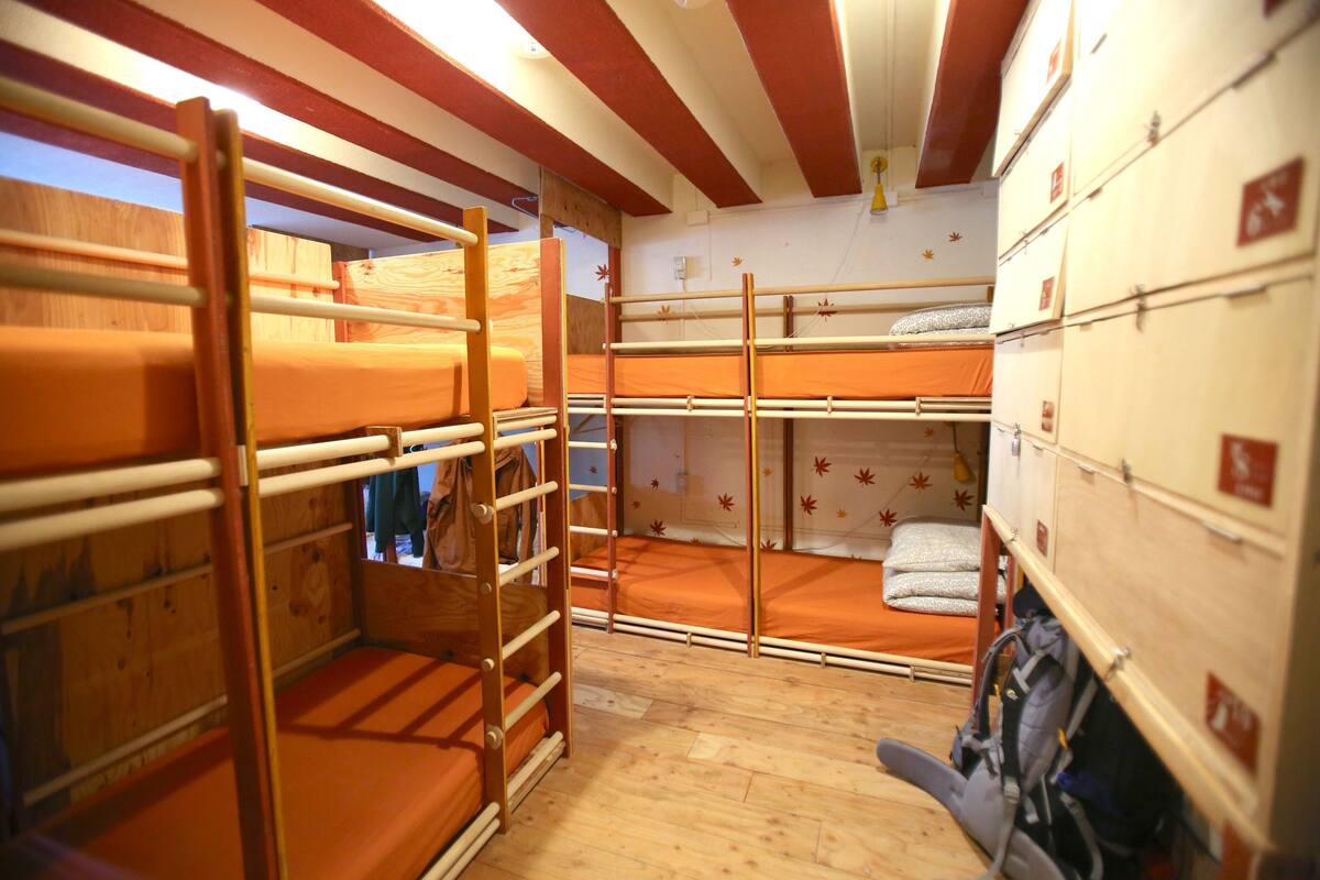 Une chambre avec des lits superposés en bois, une échelle et des armoires de rangement.