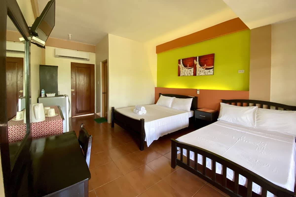 A hotel room with two beds, a desk, and a mirror.