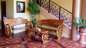 Un banco de madera con ruedas, una escalera con barandilla decorativa y una planta en maceta.