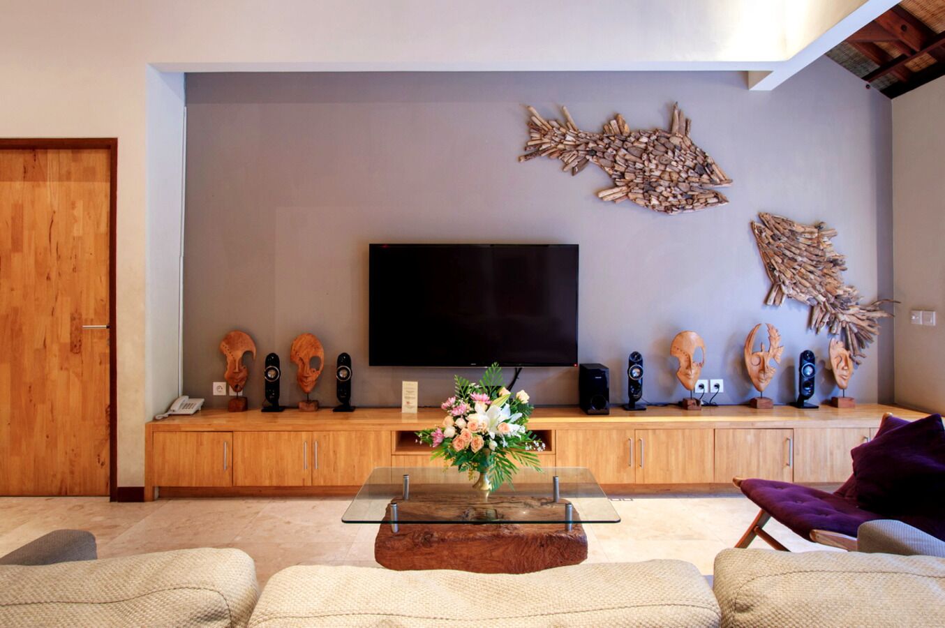 A living room with a flat-screen TV, wooden entertainment unit, and decorative masks.