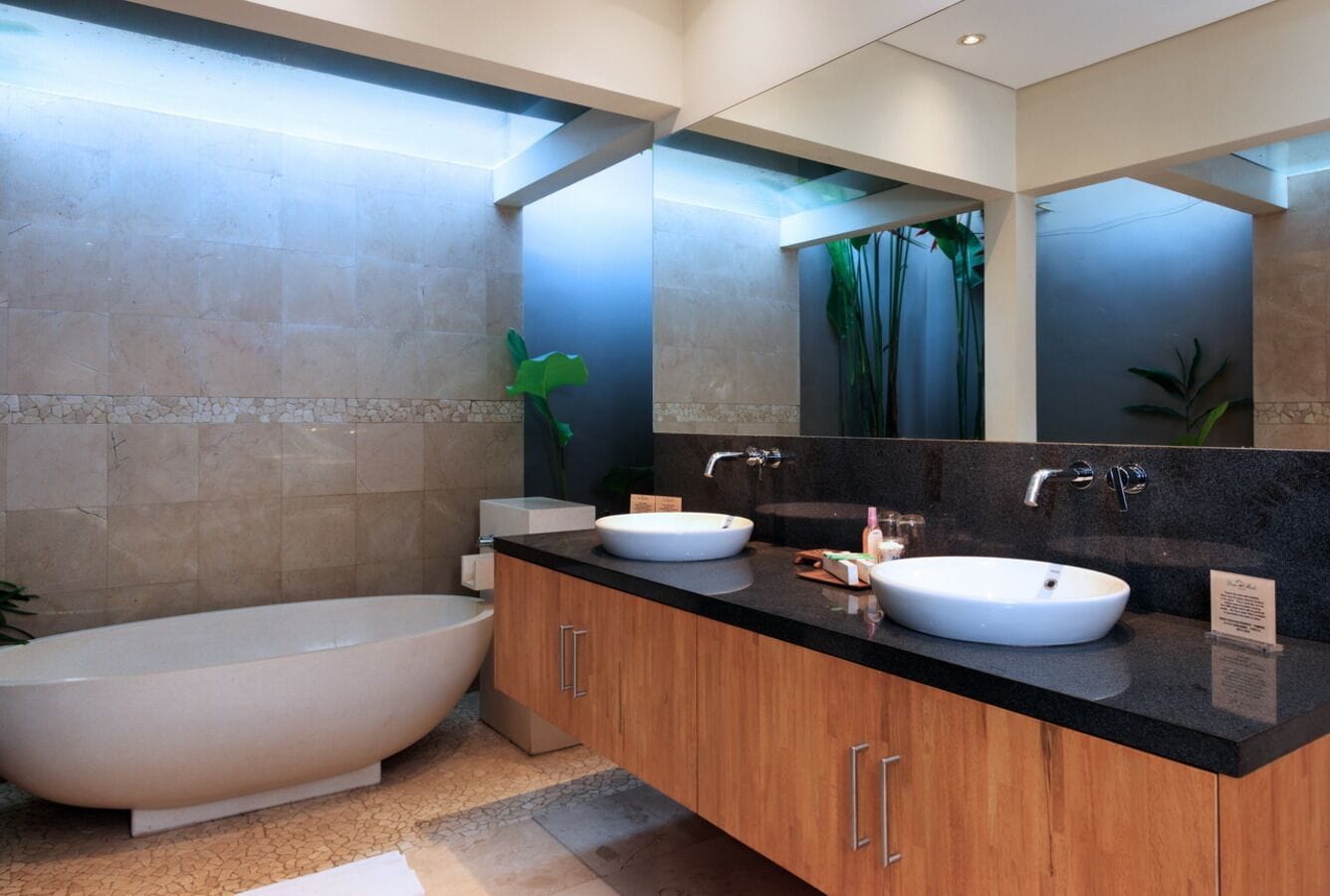 A modern bathroom with a freestanding bathtub, two sinks, and a large mirror.