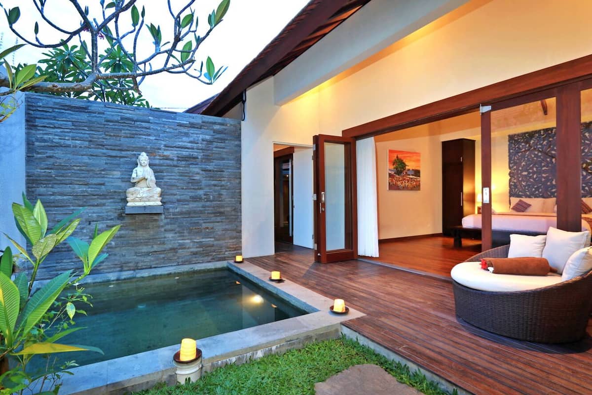 Een moderne spa met een stenen muur, een zwembadje en een rieten zithoek.