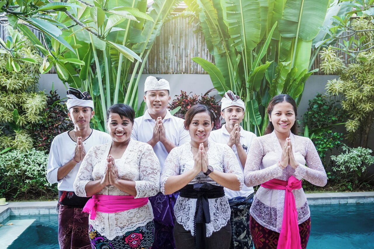 Um grupo de pessoas vestindo trajes típicos em um jardim exuberante com piscina.