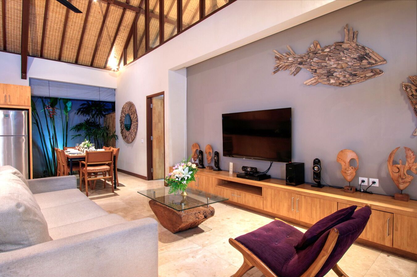 Un salón espacioso con un televisor de pantalla plana grande, armarios de madera y un comedor con mesa y sillas.