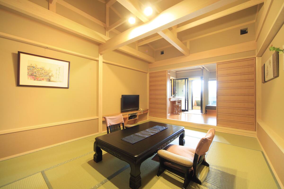 A traditional Japanese-style room with tatami flooring, a low table, and a television.