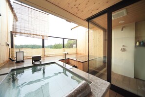 Un moderno espacio de spa con jacuzzi, suelo de madera y ducha con cerramiento de vidrio.