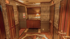 A hallway with patterned walls, wooden doors, a central counter with a lamp, and a geometric floor design. - HOTEL Salle De Bain - Adults Only (Osaka)