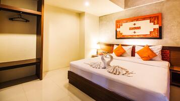 A hotel room with a bed, a wooden headboard, a wall-mounted artwork, and a hanging coat rack.