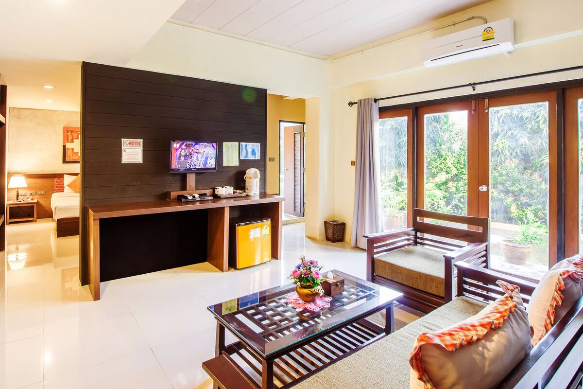 A modern hotel room with a kitchen area, a sofa, and a dining table.