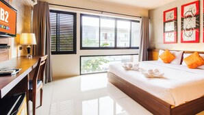 A hotel room with a large bed, a desk with a lamp, a TV, and a balcony with a view of buildings. - B2 Chiang Rai Boutique & Budget Hotel (Chiang Rai)