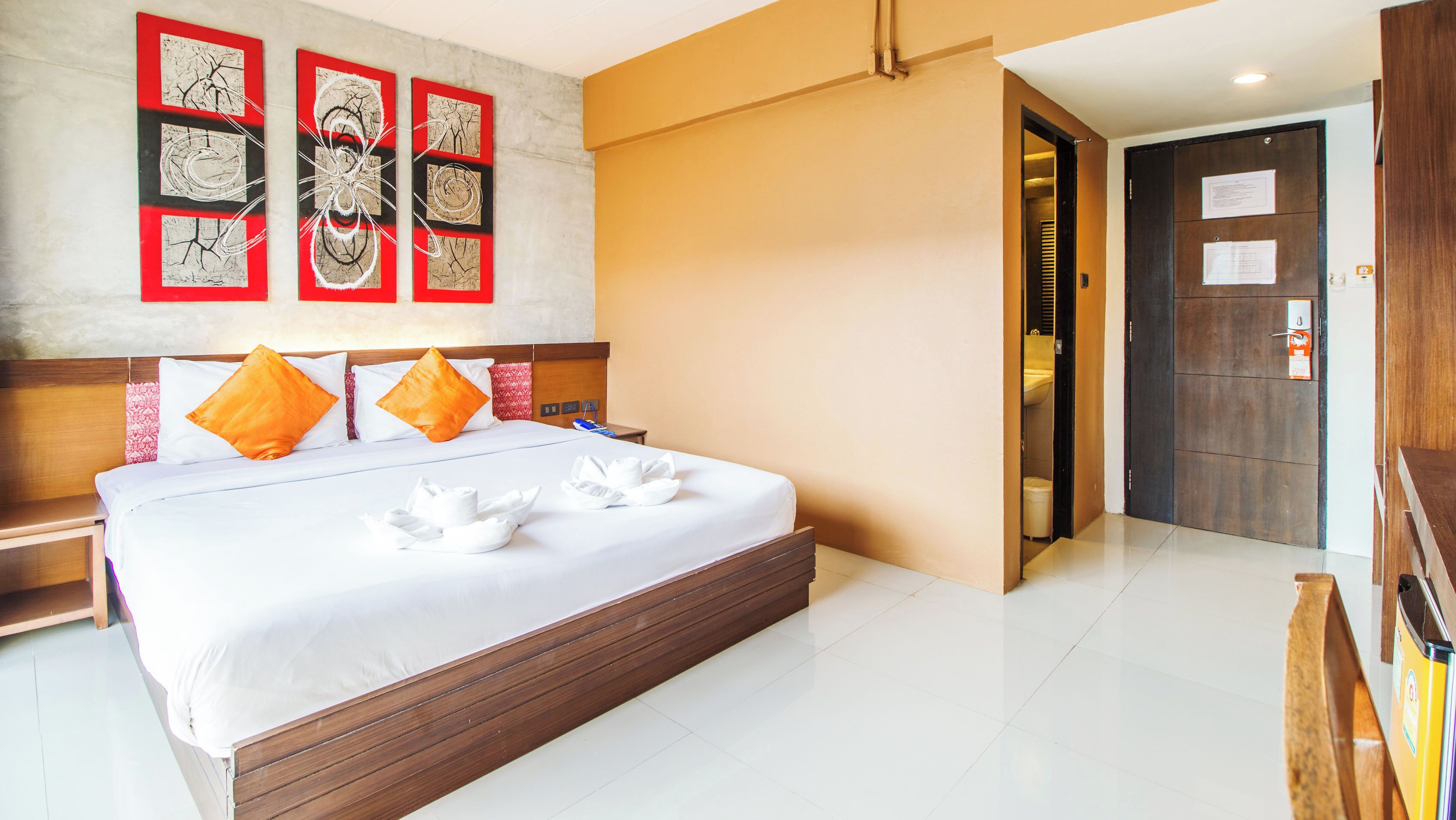 A hotel room with a large bed, wooden headboard, and a wall with abstract art.