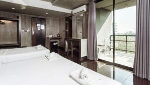 Une chambre d’hôtel avec deux lits, un bureau, un minibar et un balcon donnant sur la ville.