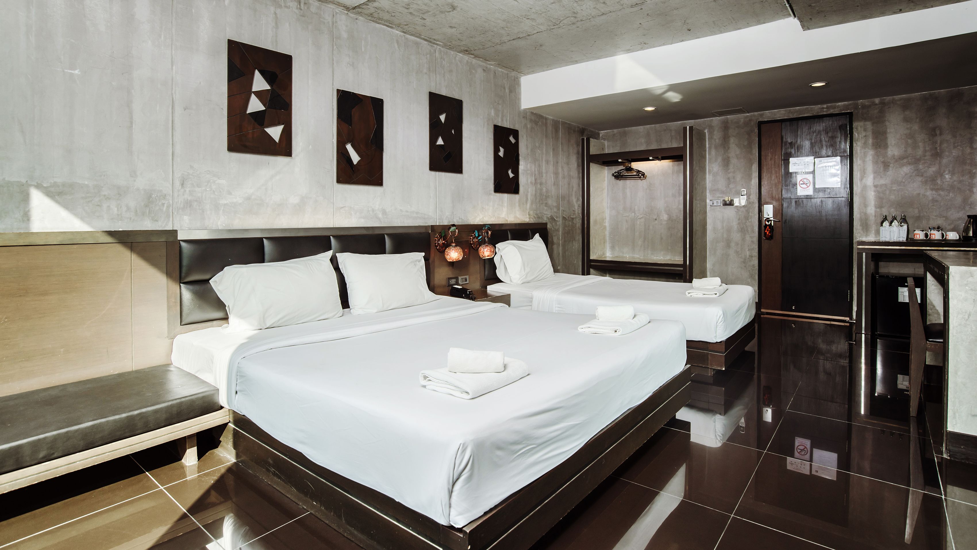 A hotel room with a large bed, two smaller beds, a minibar, and a bathroom.