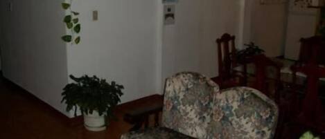Una sala de estar con un sofá floral, una mesa de centro de madera y una planta en maceta.