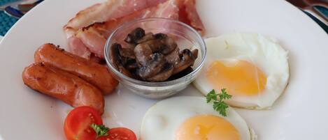 A plate with bacon, sausages, mushrooms, eggs, and tomatoes.