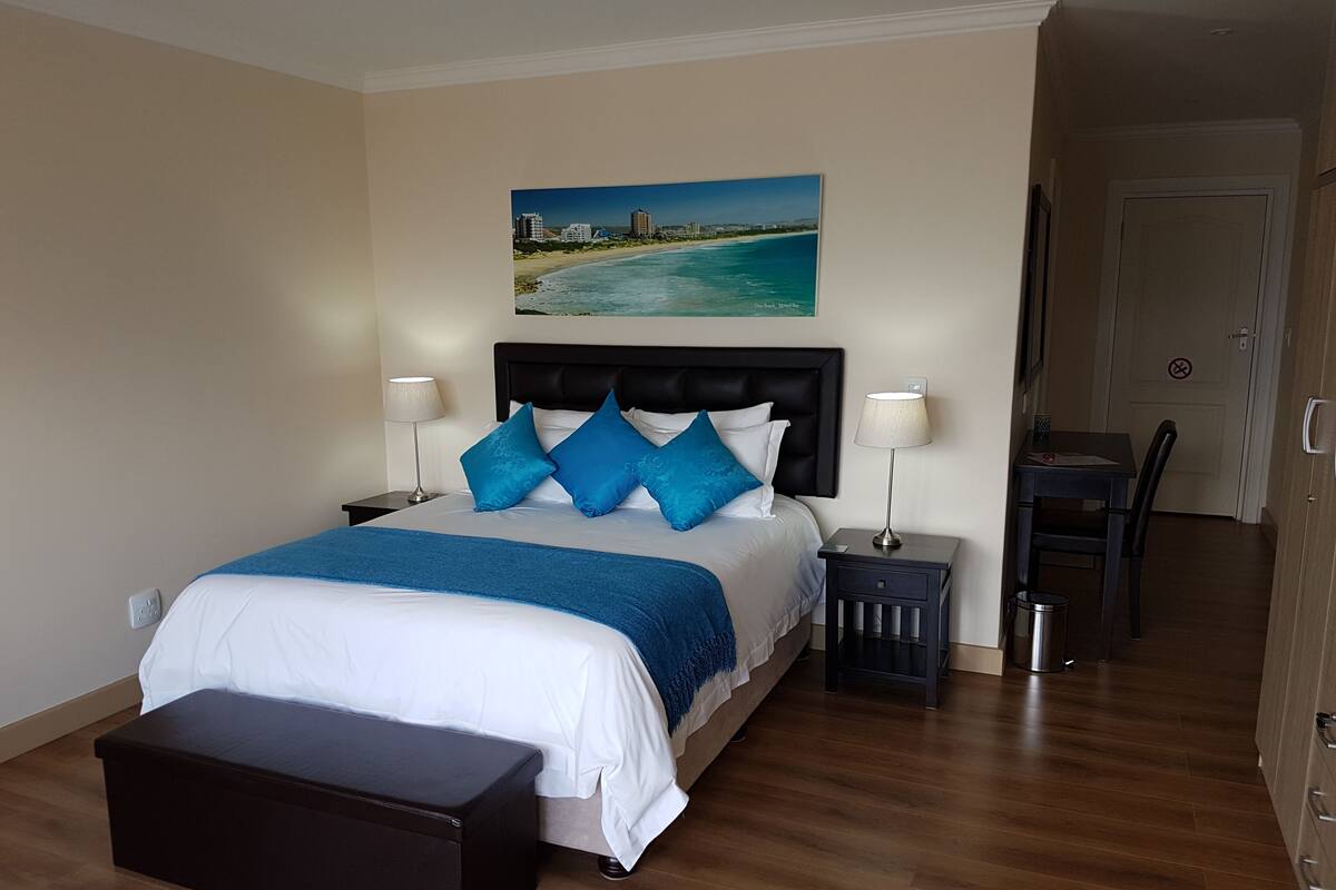 Une chambre d’hôtel avec un lit, une table de chevet, un bureau et une chaise.