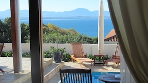 Un espace piscine avec des chaises longues et vue sur la mer.