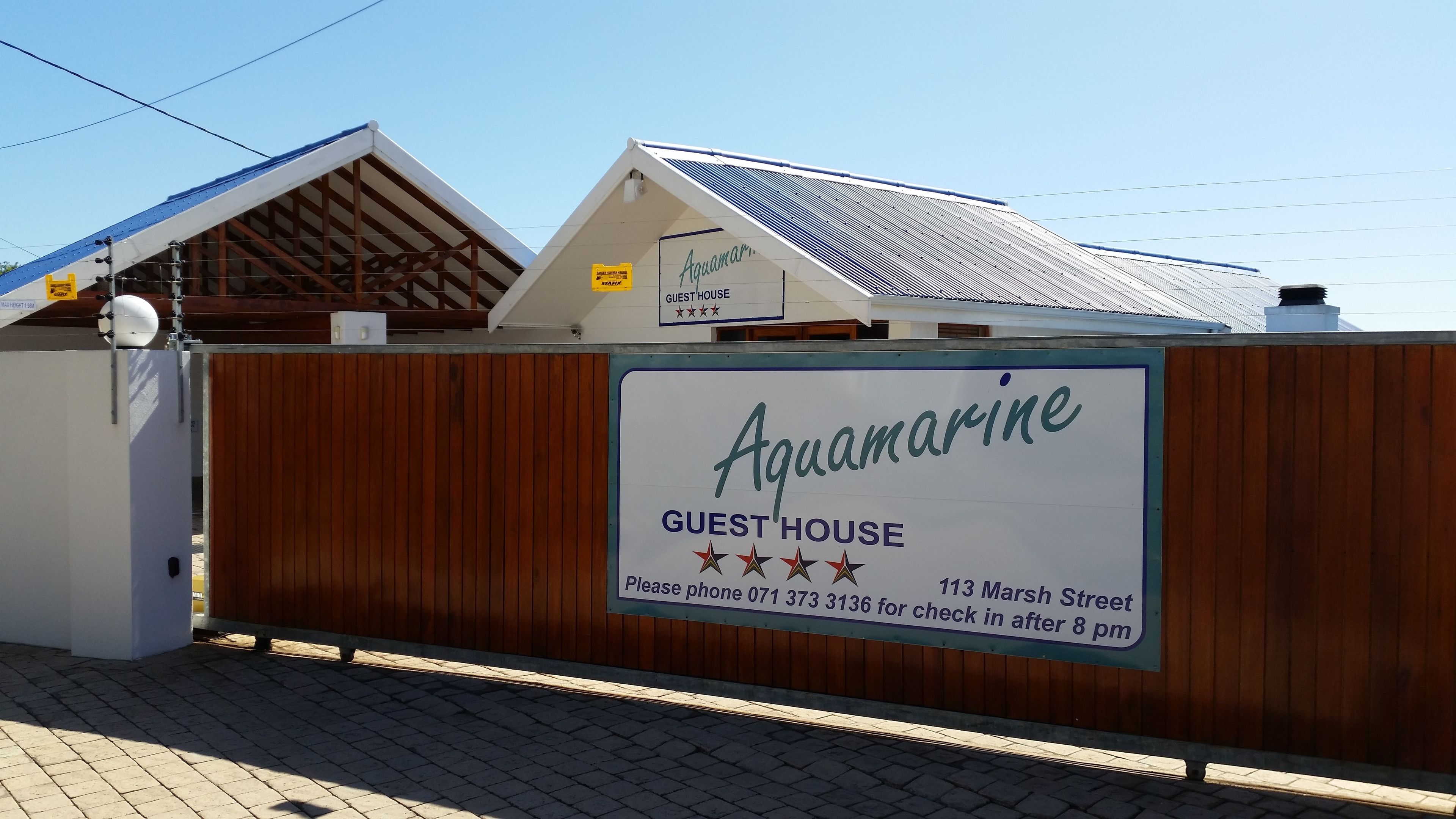 Letrero de una casa de huéspedes con el nombre 'Aquamarine' y un número de teléfono para el registro.